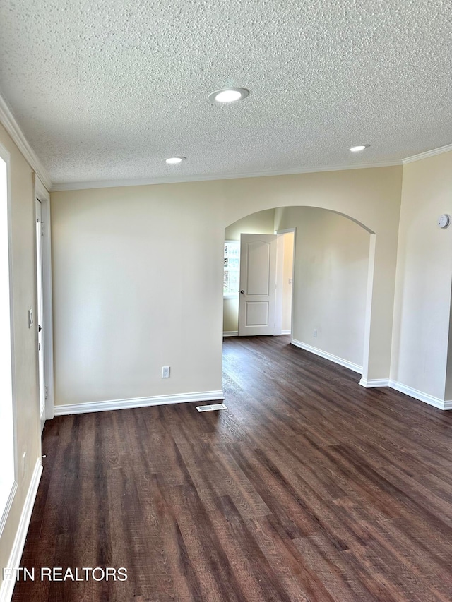 empty room with dark wood-type flooring, a textured ceiling, and crown molding