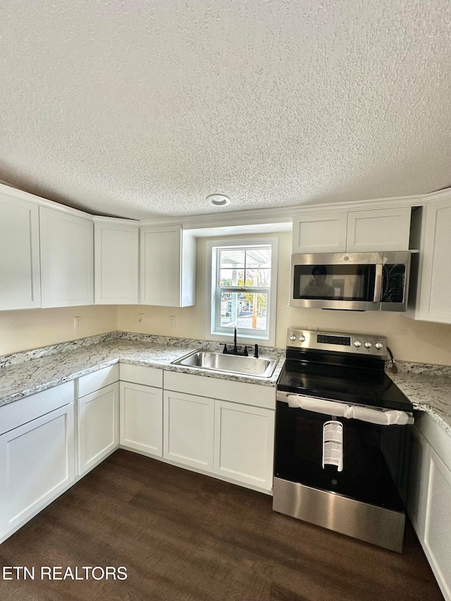 kitchen with stainless steel appliances, white cabinetry, a textured ceiling, sink, and dark wood-type flooring