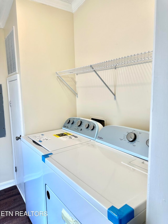 laundry room with ornamental molding, electric panel, dark hardwood / wood-style flooring, and washer and dryer