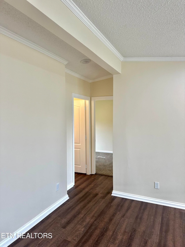 empty room with dark wood-type flooring, a textured ceiling, and crown molding