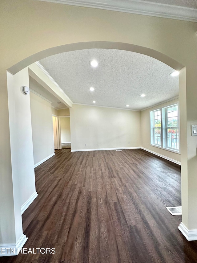 unfurnished living room with dark wood-type flooring, a textured ceiling, and crown molding