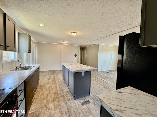 kitchen featuring visible vents, a kitchen island, light countertops, black appliances, and a sink