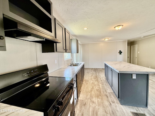 kitchen with a textured ceiling, light wood-style flooring, a sink, a kitchen island, and black electric range