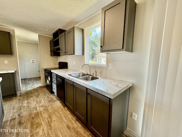 kitchen with light wood finished floors, light countertops, a sink, a textured ceiling, and black appliances