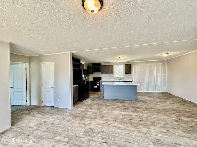 kitchen featuring stove, a kitchen island, open floor plan, light countertops, and light wood finished floors