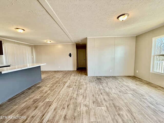 unfurnished living room with light wood-type flooring, a decorative wall, and a textured ceiling