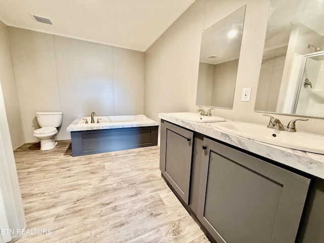 bathroom with double vanity, a sink, toilet, and wood finished floors