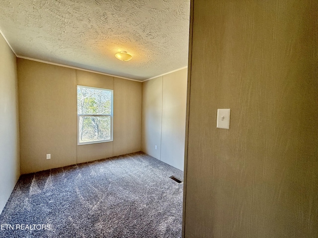 carpeted spare room with a textured ceiling, visible vents, and crown molding