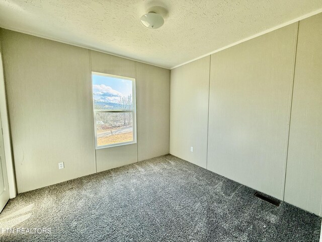 spare room with carpet floors, visible vents, and a textured ceiling