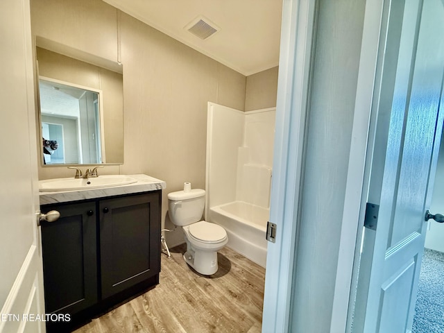 bathroom featuring toilet, wood finished floors, vanity, visible vents, and shower / washtub combination