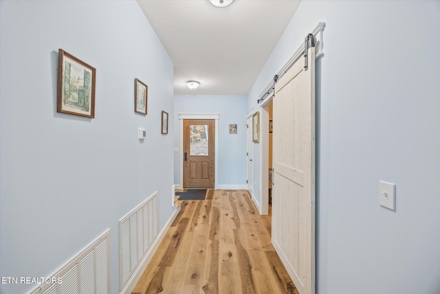 hall with light hardwood / wood-style floors and a barn door