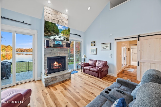 living room featuring a barn door, a healthy amount of sunlight, high vaulted ceiling, and light wood-type flooring