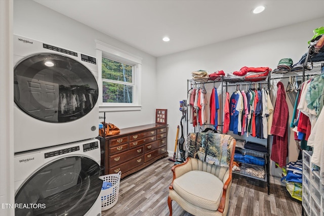 clothes washing area with light hardwood / wood-style flooring and stacked washer and clothes dryer