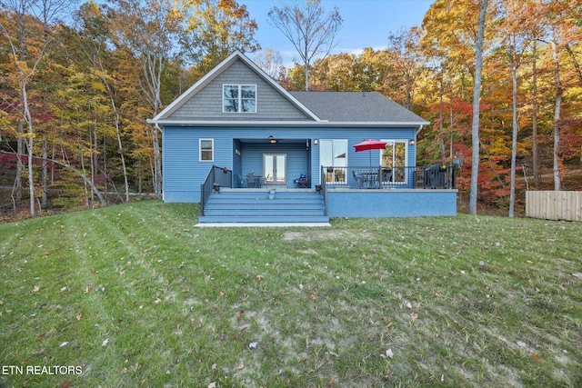 rear view of house featuring ceiling fan, a deck, and a lawn