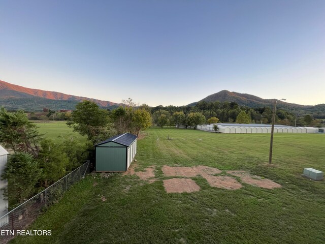 view of yard featuring a rural view, a storage unit, and a mountain view