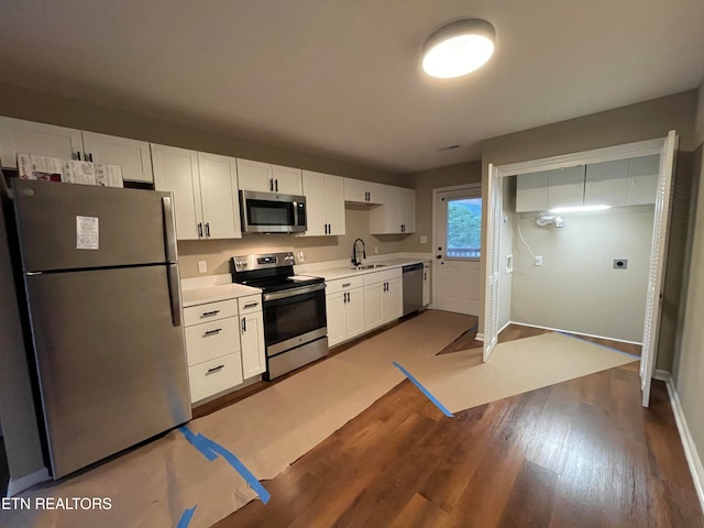 kitchen with white cabinets, stainless steel appliances, sink, and dark hardwood / wood-style floors