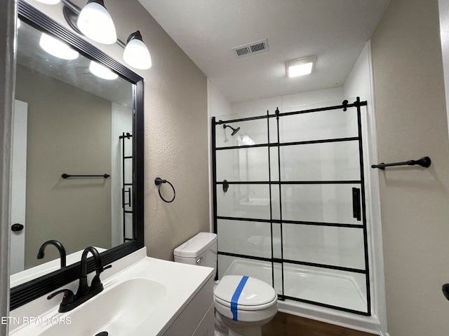 bathroom with vanity, toilet, walk in shower, and a textured ceiling