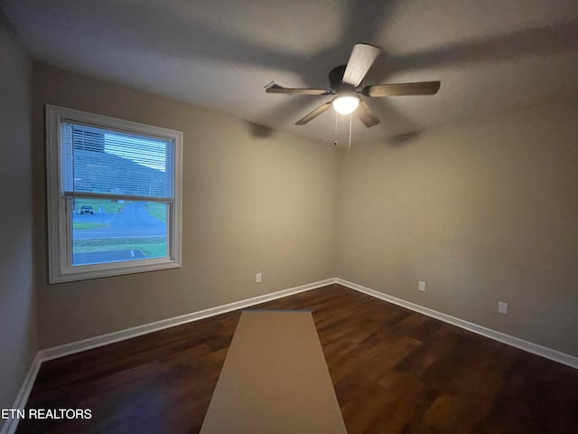 spare room with dark wood-type flooring and ceiling fan