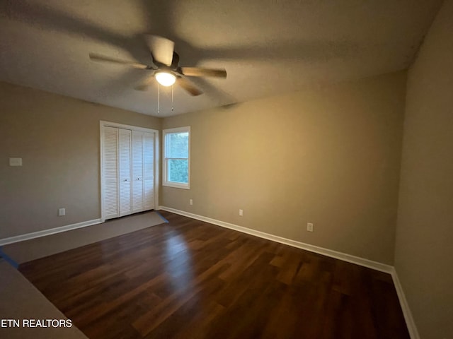 unfurnished bedroom with dark hardwood / wood-style flooring, a closet, and ceiling fan