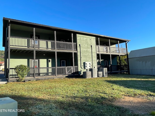 back of property with a balcony, a yard, and central AC unit