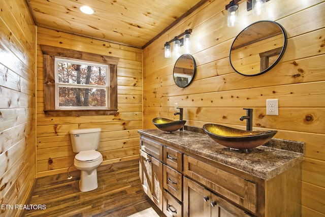 bathroom with vanity, wood-type flooring, toilet, and wood walls