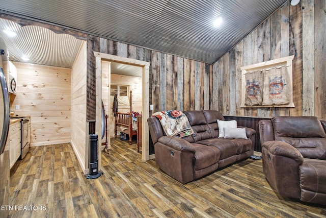 living room with lofted ceiling, wooden walls, and dark wood-type flooring