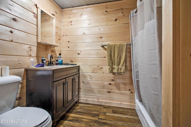 bathroom featuring toilet, vanity, wood-type flooring, and wooden walls