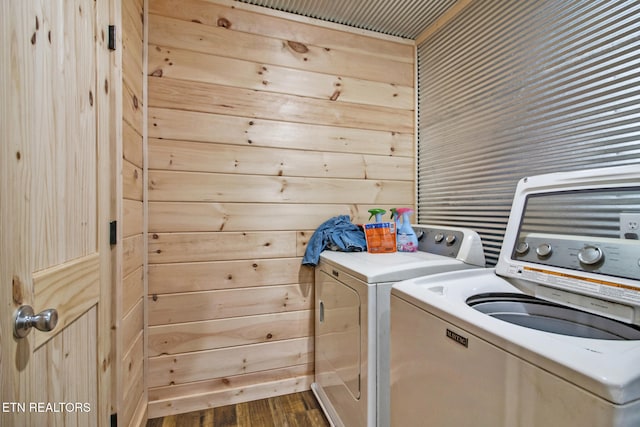 laundry area with dark wood-type flooring, washing machine and dryer, and wooden walls