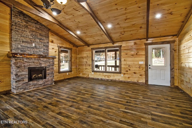 unfurnished living room with vaulted ceiling with beams, a stone fireplace, wooden walls, and dark wood-type flooring