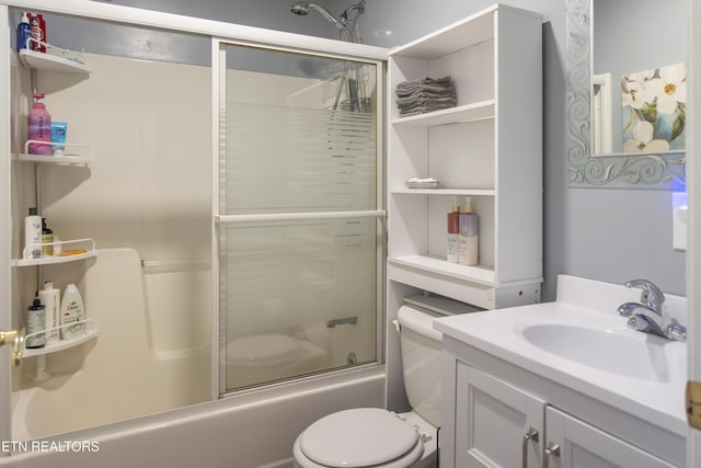 full bathroom featuring combined bath / shower with glass door, vanity, and toilet