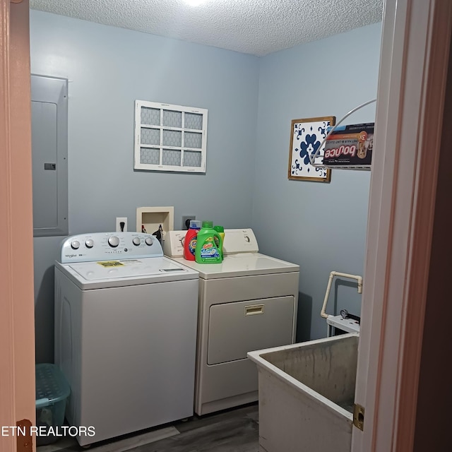 clothes washing area with electric panel, sink, dark hardwood / wood-style floors, independent washer and dryer, and a textured ceiling