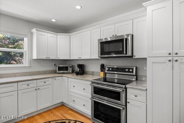 kitchen featuring light hardwood / wood-style floors, white cabinetry, and stainless steel appliances