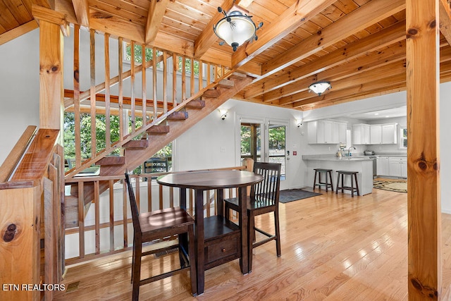 dining area with beamed ceiling, wood ceiling, sink, and light hardwood / wood-style flooring