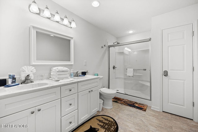 bathroom featuring vanity, a shower with shower door, and toilet