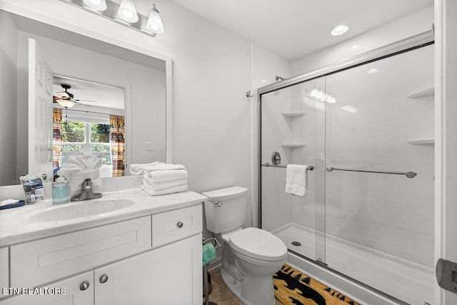 bathroom with ceiling fan, toilet, a shower with door, and vanity