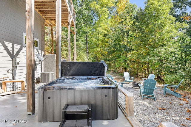 view of patio with central air condition unit, a fire pit, and a hot tub