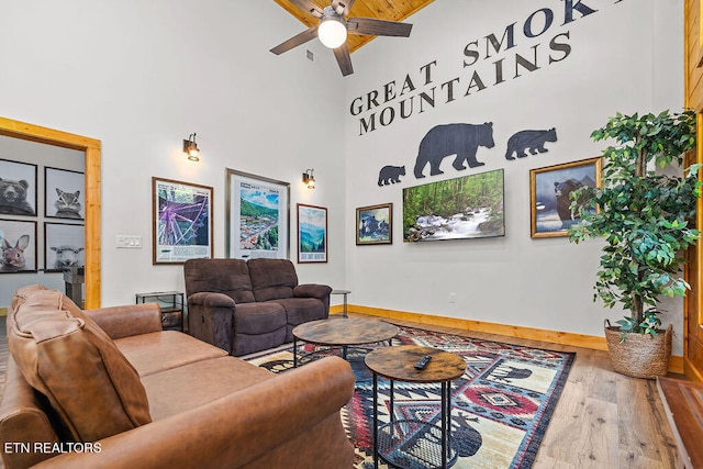 living room with hardwood / wood-style floors, ceiling fan, and high vaulted ceiling