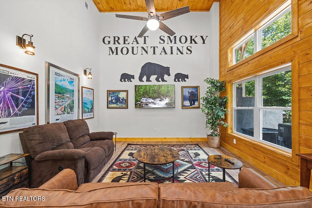 living room featuring hardwood / wood-style floors, wooden ceiling, high vaulted ceiling, wooden walls, and ceiling fan