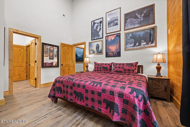 bedroom with hardwood / wood-style floors and a towering ceiling