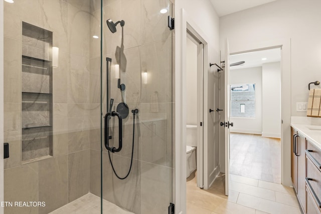 bathroom featuring tile patterned flooring, vanity, toilet, and an enclosed shower