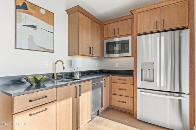 kitchen featuring stainless steel appliances, sink, and light hardwood / wood-style flooring