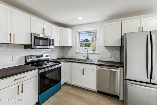 kitchen featuring white cabinetry, appliances with stainless steel finishes, sink, and light wood-type flooring