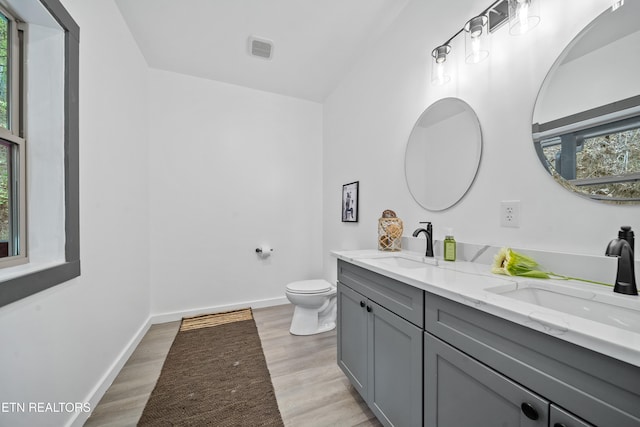 bathroom featuring toilet, vanity, hardwood / wood-style floors, and plenty of natural light