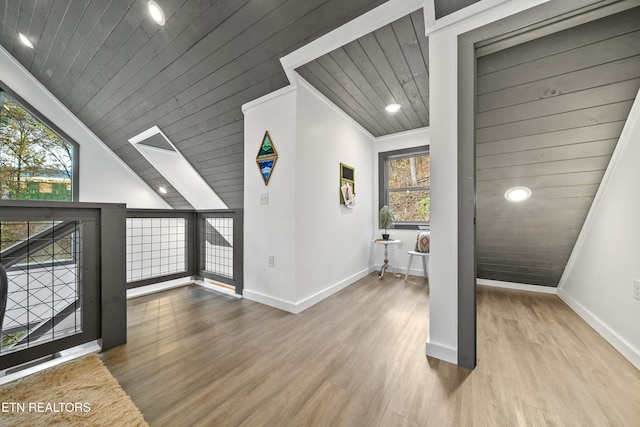 hall with lofted ceiling with skylight, a wealth of natural light, wooden ceiling, and ornamental molding