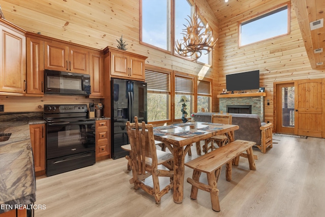 dining space with a fireplace, light wood-type flooring, high vaulted ceiling, and a notable chandelier