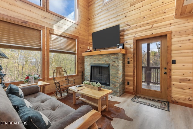 living room featuring a towering ceiling, a fireplace, wood-type flooring, and wooden walls