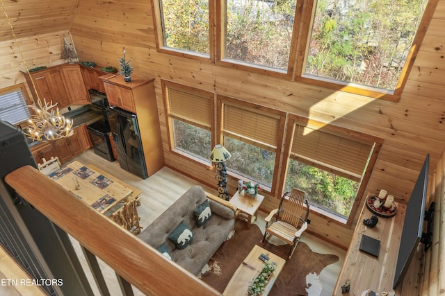 living room featuring high vaulted ceiling, light hardwood / wood-style floors, and wood walls