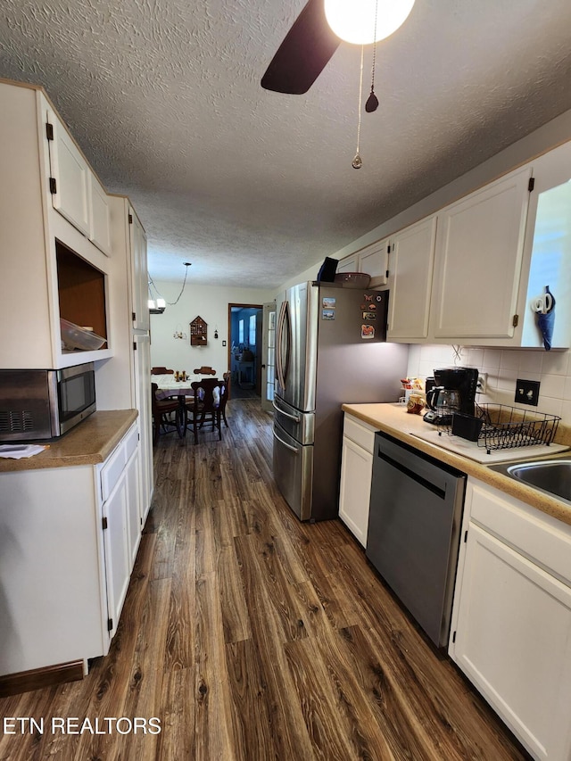 kitchen with appliances with stainless steel finishes, white cabinets, and dark wood-type flooring