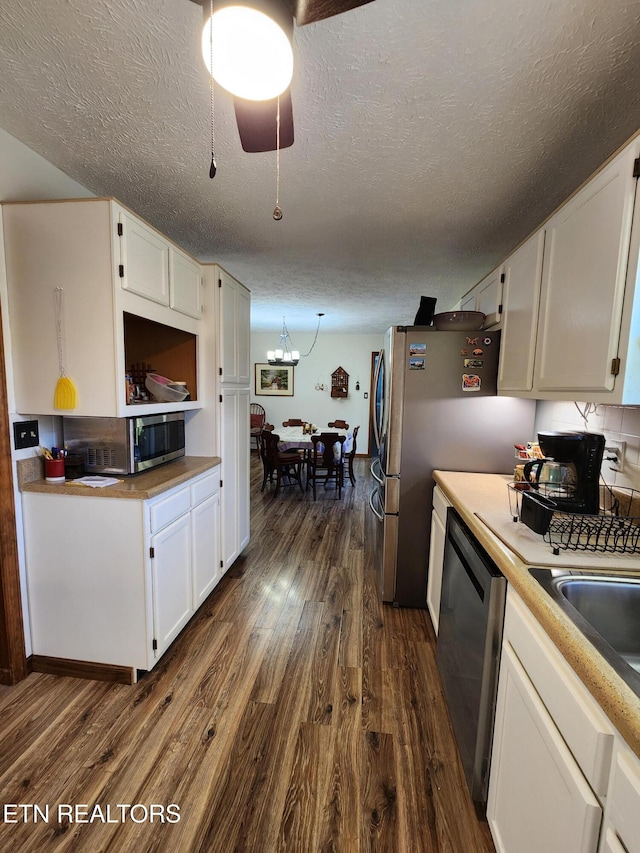 kitchen featuring a textured ceiling, white cabinets, stainless steel appliances, and dark hardwood / wood-style flooring