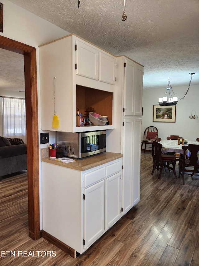 kitchen with white cabinetry, decorative light fixtures, and dark hardwood / wood-style flooring